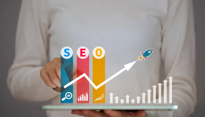 How does local seo works A person holding a tablet displaying seo growth charts with upward arrows and a rocket icon, symbolizing the impact of local seo on business growth and success.