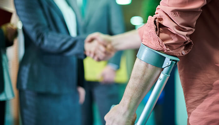 How long would it take to settle a personal injury case The picture shows a person on crutches shaking hands, signifying resilience in a personal injury cases.