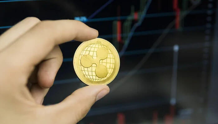Ripple-tycoonstory | tycoonstory media Person holding a ripple xrp coin in front of a trading chart, emphasizing crypto trading activity in the crypto casino market.