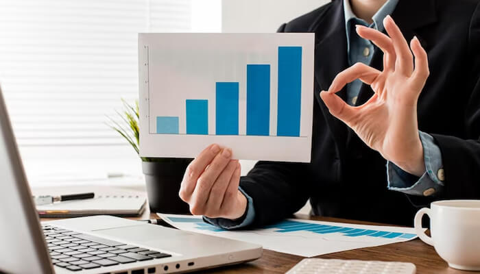 Scaling Professional presenting an upward growth bar chart in an office setting, highlighting performance tracking and success metrics in a software startup.