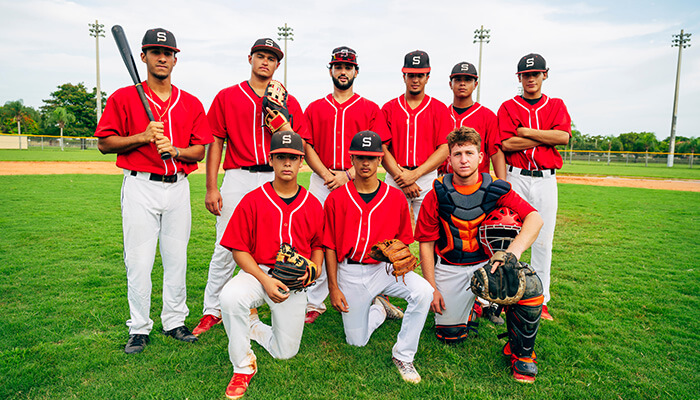 Team-building baseball outing A baseball team posing for a group photo on the field, dressed in red jerseys for a baseball game.