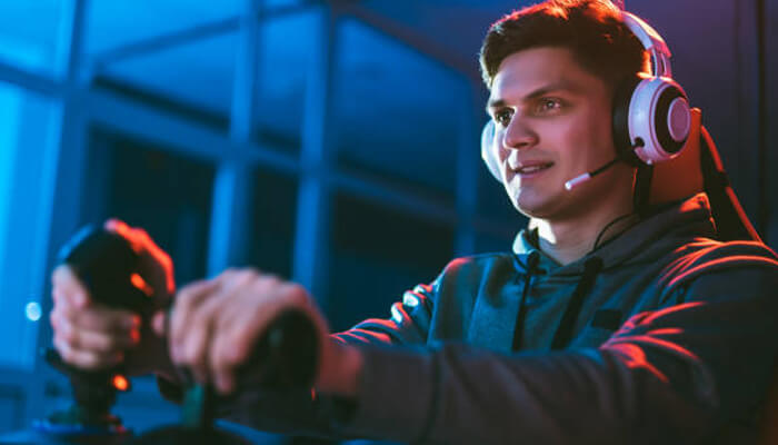 Tips and strategies for winning in jetx - tycoonstory | tycoonstory media A concentrated gamer with a headset holds a joystick, lost in jetx game in a blue-lit room.