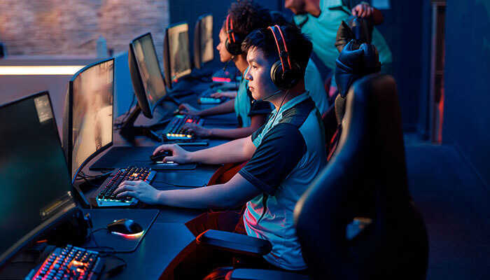 Understanding server hosting options A group of gamers in a gaming center, each using a computer, emphasizing the importance of powerful video game servers for multiplayer gaming sessions.