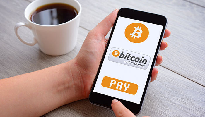 Bitcoin payments Person holding a smartphone showing bitcoin payment screen with “bitcoin accepted here” message, illustrating bitcoin being used for digital payments and transactions.