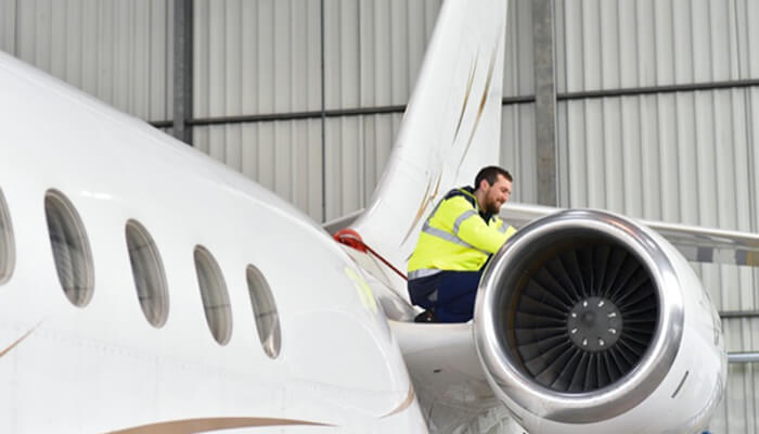 Private jet Technician inspecting the engine of a private jet, emphasizing the technical work involved in ensuring the jet's performance.