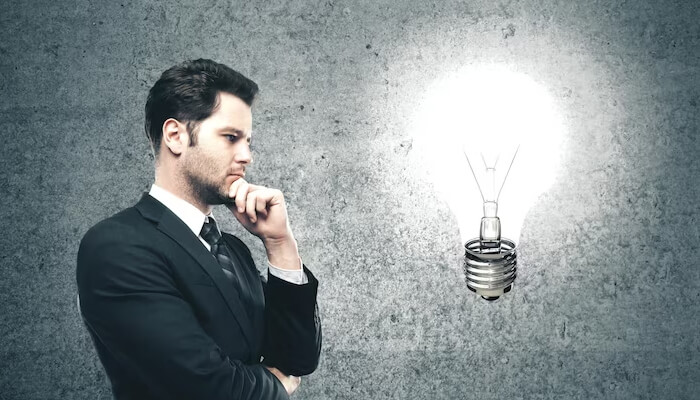Critical thinking A businessman thoughtfully looking at a glowing light bulb, symbolizing innovative strategies for hiring early-stage candidates.