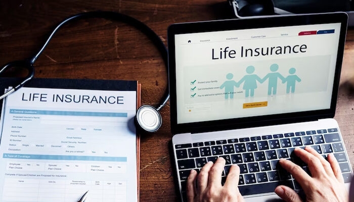 Different types of life insurance Life insurance application process shown with a laptop displaying a life insurance webpage and a printed insurance form beside a stethoscope.