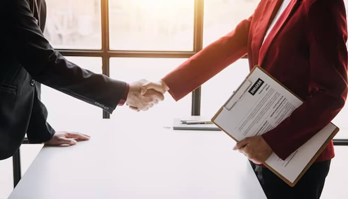 Why hire them Business professionals shaking hands, symbolizing a successful partnership or agreement in procurement consulting firms.