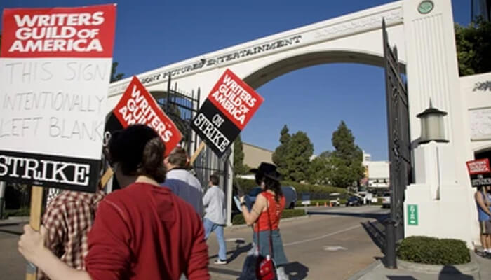 Hollywood writers Writers guild of america protesters holding strike signs, with one sign left blank intentionally, at the studio gates.