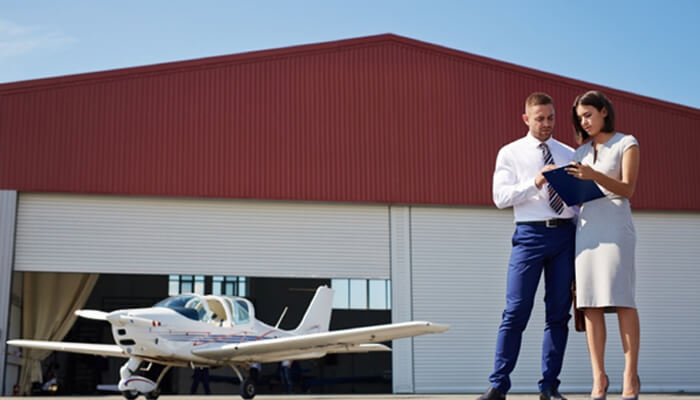 Private jet Business professionals discussing aircraft options outside a private jet hangar, with a private jet in the background.