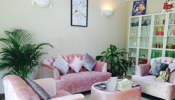 Joz salon & spa A cozy and elegant salons space with pink velvet sofas, plants, and beauty products displayed, offering a relaxing atmosphere.