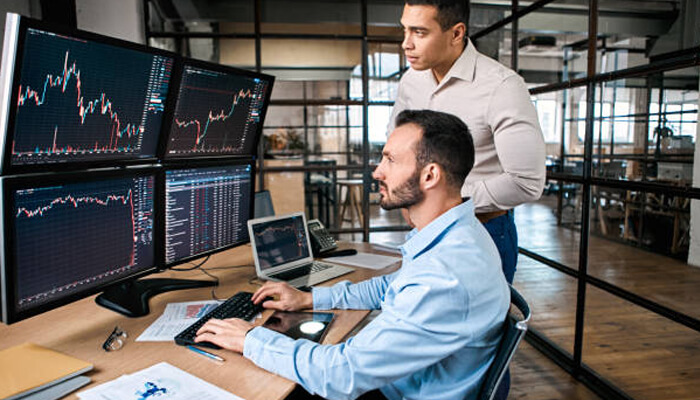 Surgetrader review Two traders reviewing live stock market data in a modern prop trading setup — teamwork environment like surgetrader-funded accounts.