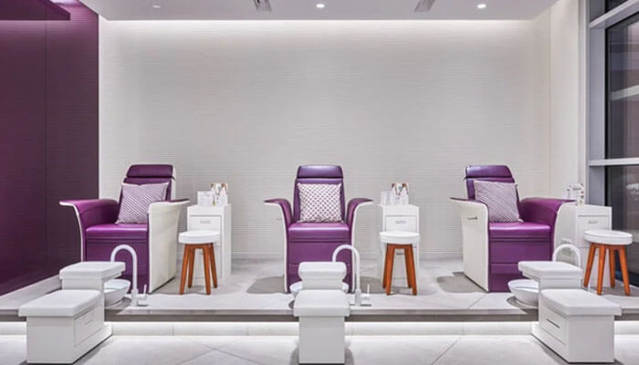 The nail spa A clean and minimalist nail salon with purple chairs and modern styling, offering an elegant space for clients to relax during treatments.