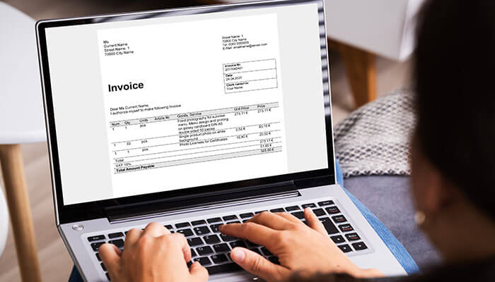 Transforming your practice with a legal invoice template A person working on a laptop while reviewing a legal invoice displayed on the screen, showing detailed billing information and payment breakdown.