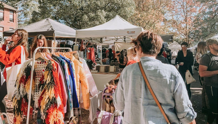 Business ideas Shoppers browsing at a vibrant market, representing business ideas related to retail, fashion, and market stalls.