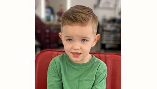 Long and layered little boy haircuts Young boy with a neat side-swept hairstyle, a classic choice for little boy haircuts.