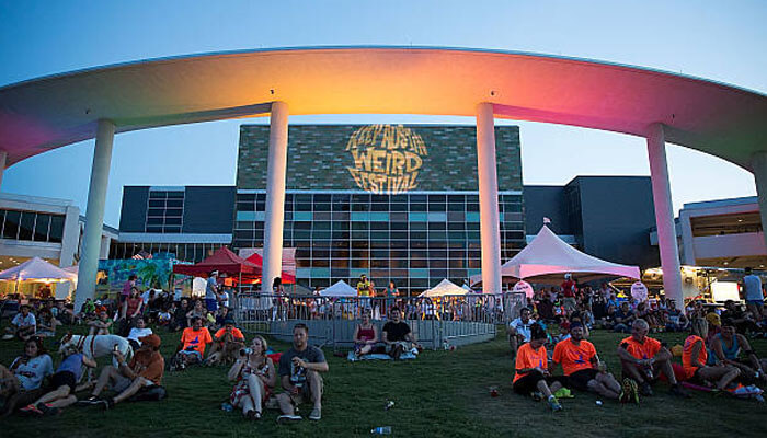 Tourists Tourists enjoying an outdoor festival with music and colorful lights at dusk.