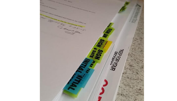 Refinansieringslån Refinansieringslån paperwork stack with highlighted loan terms and signed financial documents on a desk.