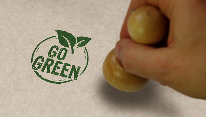 Use recycled paper Hand stamping a'Go Green' logo on paper, emphasizing eco-friendly practices in business printing for sustainability.