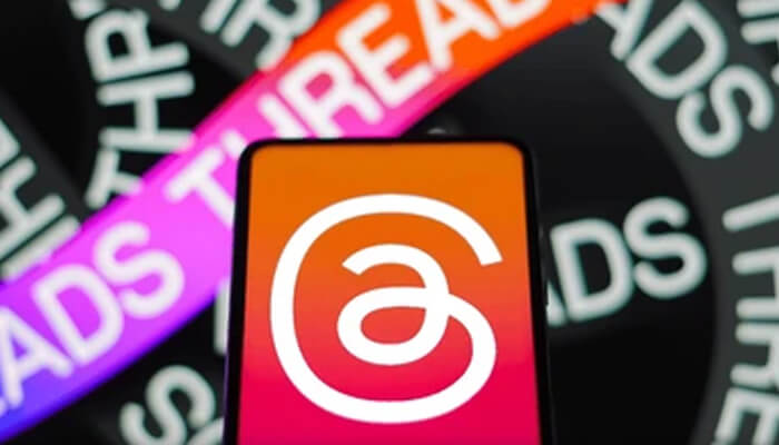 Charge of threads Close-up of a phone displaying the threads app logo with colorful threads text in the background, showcasing the app's branding