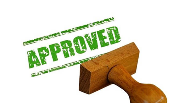 Refinansieringslån Approved loan stamp with wooden seal symbolizing successful loan approval and completed financing process.