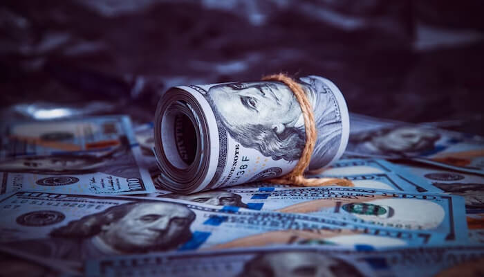 Dollar - tycoonstory | tycoonstory media A close-up of rolled us dollars surrounded by scattered bills, illustrating the value and importance of the us dollar in the global financial system.