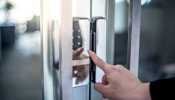 Digital lock Locking access control system showing a person entering a secure keypad code on a glass door.