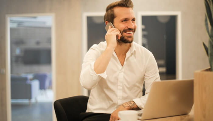 Investment syndicates A professional speaking on the phone while working on a laptop in an office, illustrating communication, deal coordination, and networking within investment syndicates.