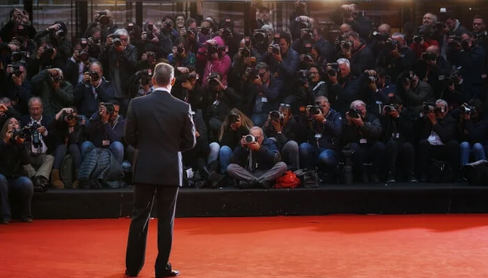 Tom hanks Tom hanks facing a crowd of photographers on the red carpet, capturing his moment of fame at a major event.