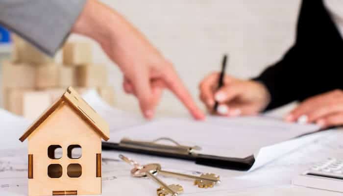 Vacation rentals A "for rent" sign in front of a white house or resort building under a sunny sky, indicating vacation rentals available at the property.