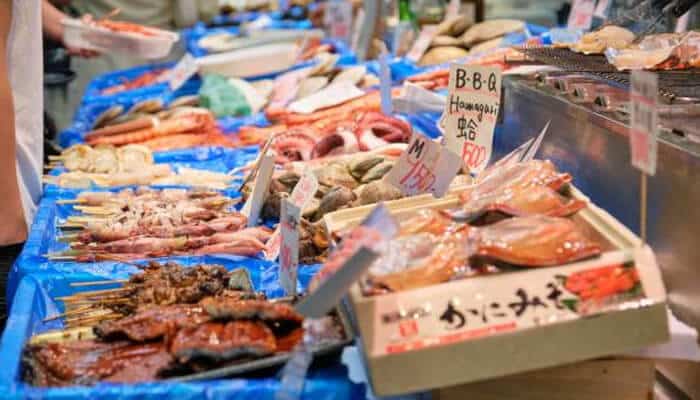 Japanese seafood Japanese seafood market stall displaying fresh fish, shellfish, and bbq skewers on ice.