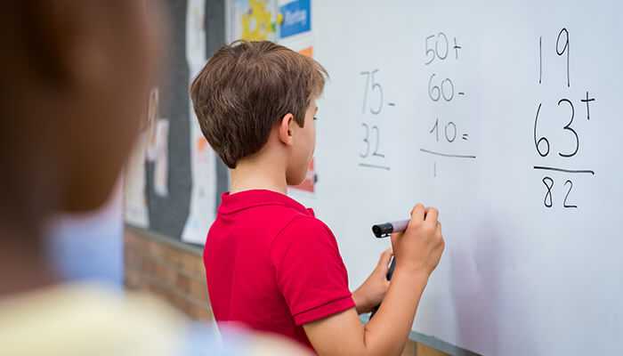 Year 7 maths worksheets Student solving arithmetic problems on a classroom whiteboard, demonstrating year 7 maths worksheets in action.