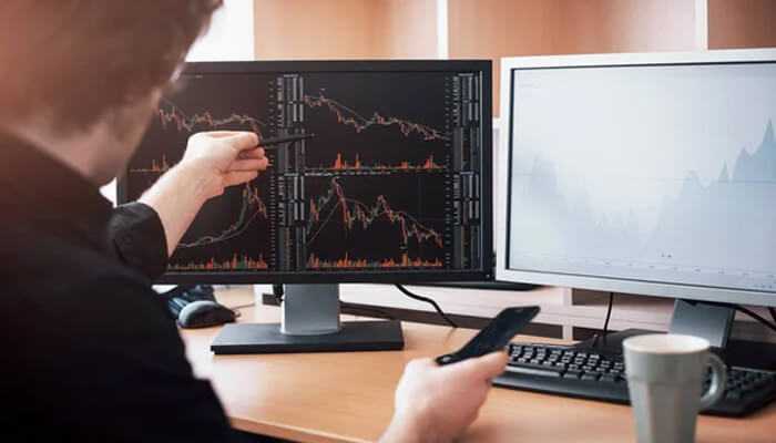 Activity scanner Person analyzing market trends on dual monitors, using an activity scanner tool to track financial data and stock performance.