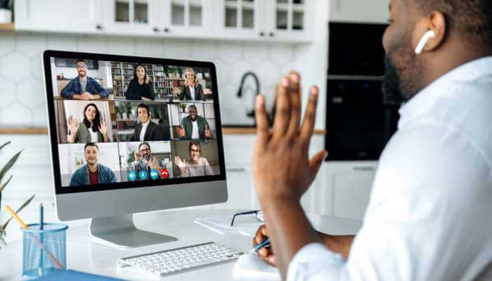 Personal preferences A managers participating in a virtual team meeting, waving to colleagues on a video call from a home office.