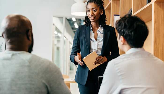 Empowerment Professional woman leading a discussion with colleagues in a modern office, representing workplace leadership and empowerment.