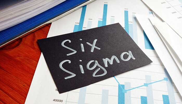 What is the six sigma methodology A black card with the words six sigma written on it, placed on financial charts, symbolizing the use of six sigma in data analysis and process improvement.