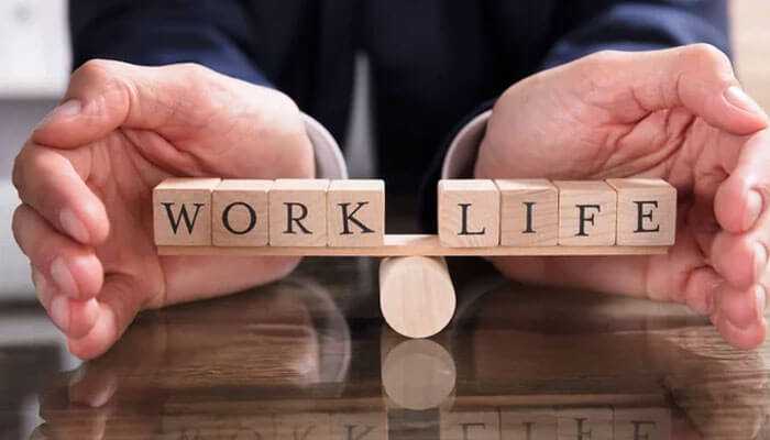 Better work-life balance - tycoonstory | tycoonstory media Hands protecting wooden blocks spelling work life, symbolizing a balanced and healthy workspace.