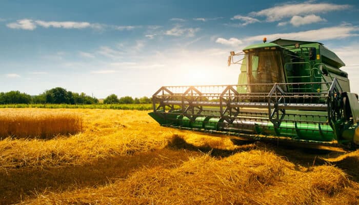 Agribusiness loans A combine harvester working in a golden field during harvest season, symbolizing the agricultural industry and farming operations.