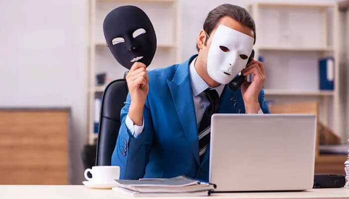 Conversion fraud - tycoonstory | tycoonstory media Man holding theatrical masks while working on a laptop, symbolizing online deception and ad fraud activities.