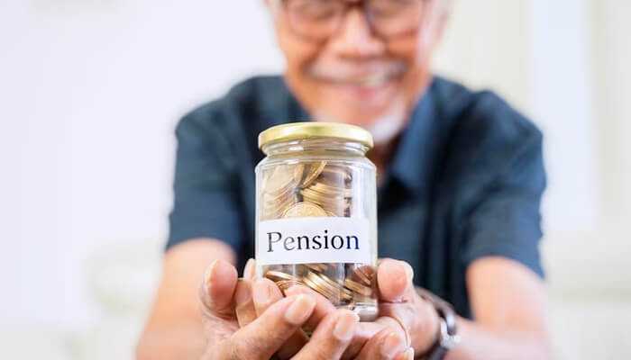 Pension scheme A close-up of an elderly person's hands holding a small jar filled with gold coins labeled "Pension," symbolizing retirement savings.