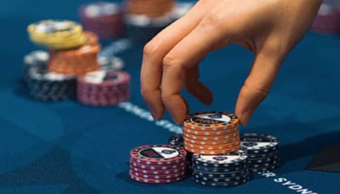 Online Slots Close-up of a hand stacking poker chips on a casino table, symbolizing gambling, strategy, and poker games.
