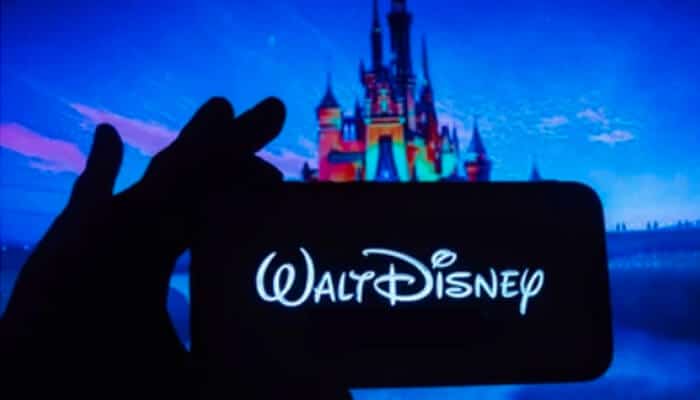 Walter elias disney Hand holding a phone displaying the walt disney logo, symbolizing the global reach of walter elias disney entertainment empire.