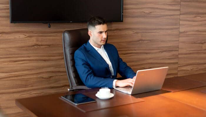 Mba Mba graduate working on a laptop in a corporate meeting room, focusing on business strategy and leadership tasks.