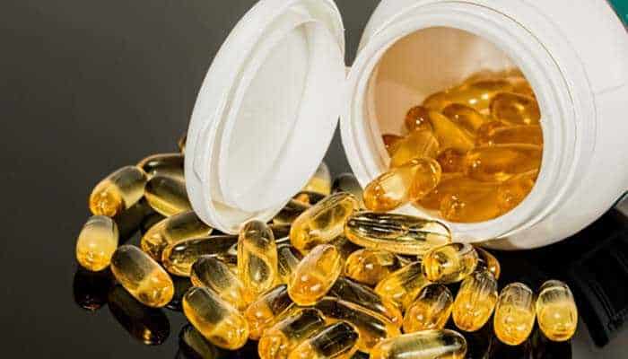 Resveratrol supplement - tycoonstory | tycoonstory media Open bottle of golden gel capsules scattered around, possibly representing dietary supplements or vitamins.