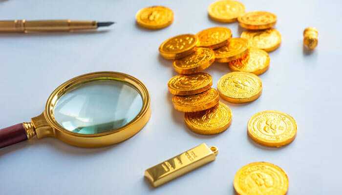 Gold in economic landscape Magnifying glass, pen, and a pile of shiny gold coins and a tiny gold bar, representing investment in the gold in economic landscape.