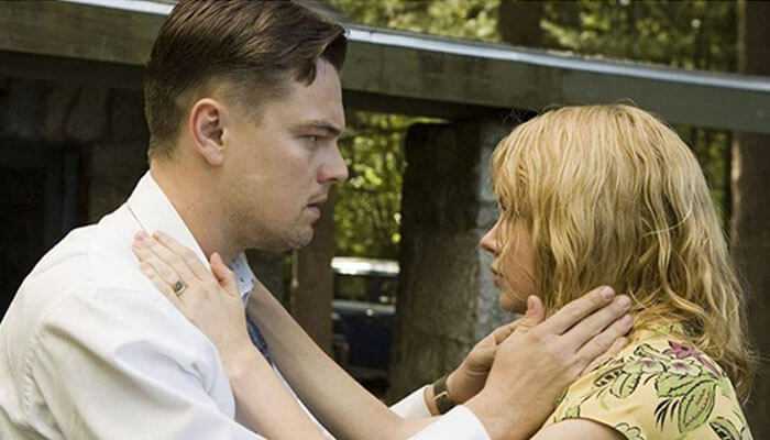 Shutter island - tycoonstory | tycoonstory media A close-up, dramatic movie still featuring a man and a blonde woman. The man, on the left (likely leonardo dicaprio), is wearing a white collared shirt and holds the woman's face with his hands.