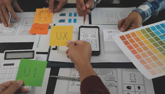Uiux design agency - tycoonstory | tycoonstory media Ui/ux design process in action with designers creating wireframes, user flows, and interface layouts during a team workshop
