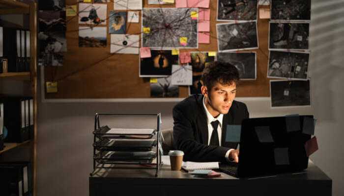 You suspect fraud in your business - tycoonstory | tycoonstory media Private investigator analyzing evidence on a laptop in an investigation room filled with photos and case files.