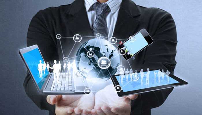 Access to expertise and latest technologies - tycoonstory | tycoonstory media A business professional holding digital devices like a laptop, tablet, and smartphone, with a networked globe and icons representing global connectivity, communication, and technology integration in business