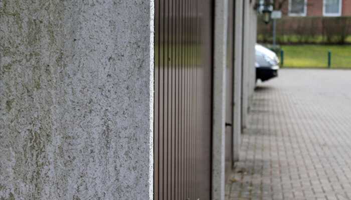 Side view of a garage door beside a concrete wall, illustrating the importance of proper professional garage door installation to avoid costly mistakes. Professional garage door installation